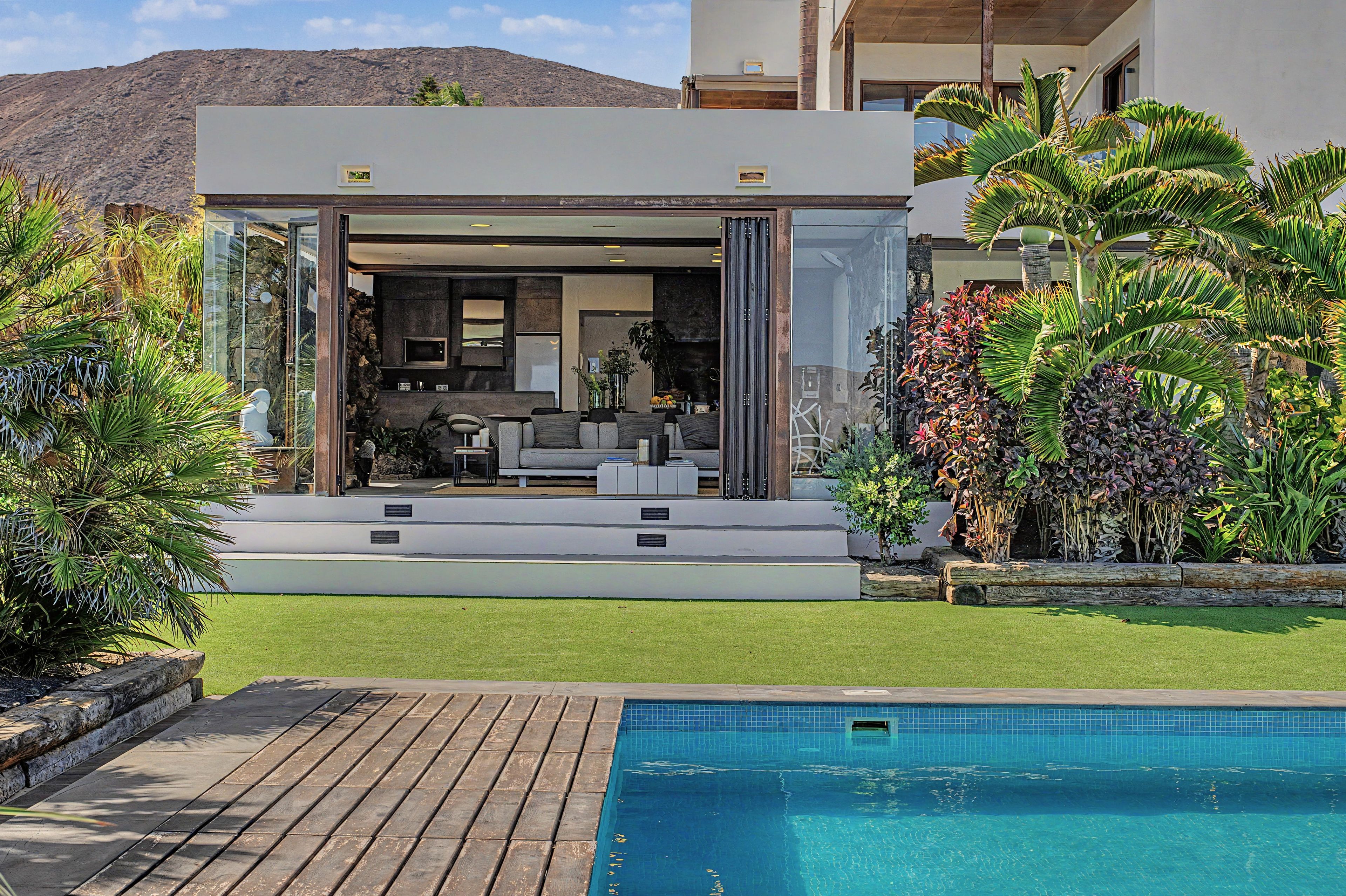 A modern house with a pool, a patio, and a view of the mountains.