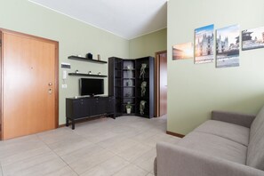 A living room with a sofa, a TV, a cabinet, and a corner bookshelf. - GuestHost - Spacious 70 sqm apartment, ideal for up to 6 people, located on the eighth floor of a building with an elevator.The accommodation is strategically located in the Brenta district, within the 4th district, just steps from the M3 Brenta metro  (Milan)