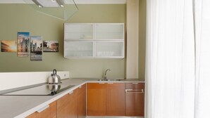 Una cocina con armarios de madera, un lavamanos de acero inoxidable y un hervidor.