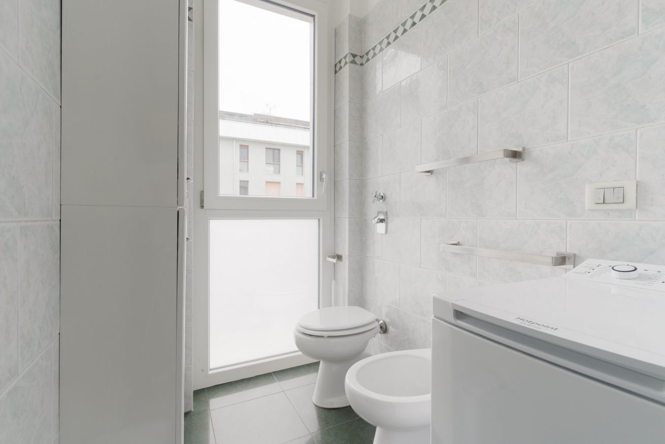 Ein Badezimmer mit Toilette, Waschbecken und Fenster.