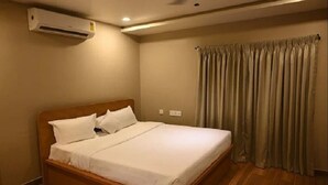Een opgemaakt bed in een kamer met een houten hoofdeinde, beige wanden en een raam met gordijnen.