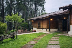 Uma casa de madeira com telhado de telhas, rodeada por um gramado bem cuidado e um caminho de pedra.