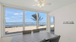 Ein Zimmer mit großem Fenster mit Blick auf einen Strand, einem Deckenventilator und einem Schild mit der Aufschrift 'TOWELS'.