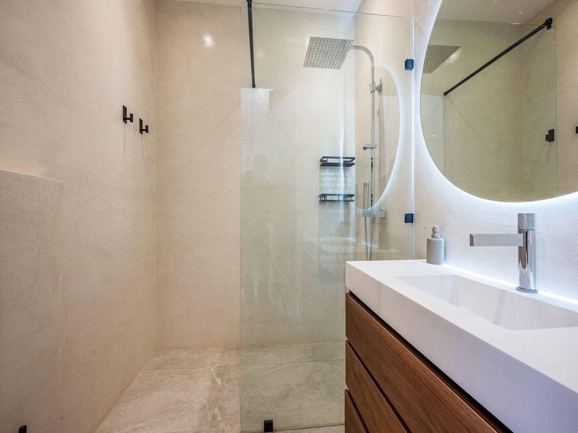 Een moderne badkamer met een douchecabine van glas, een wit wastafelmeubel met een houten lade en een grote spiegel.