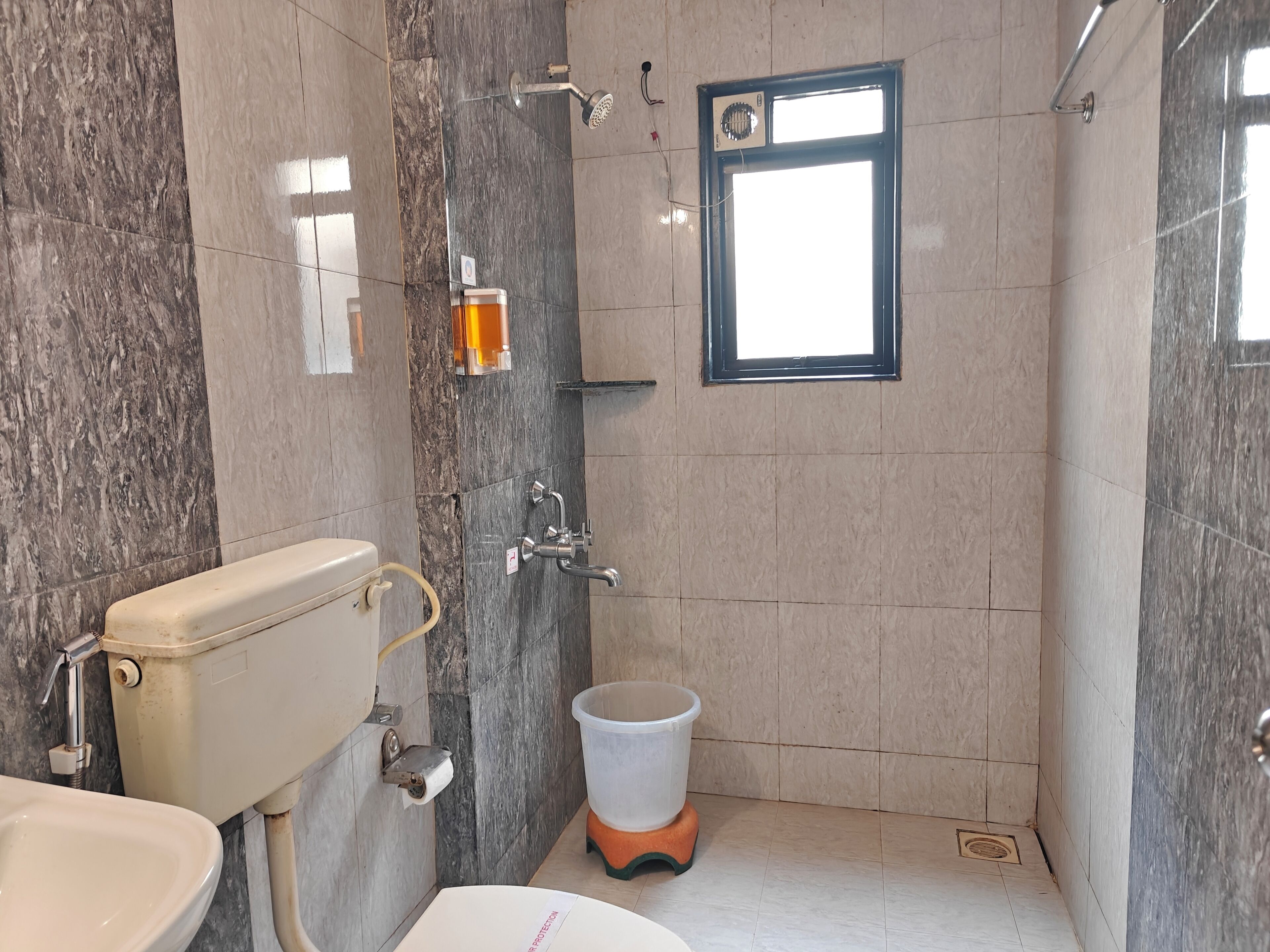Ein Badezimmer mit Toilette, Waschbecken, Dusche und einem Fenster.