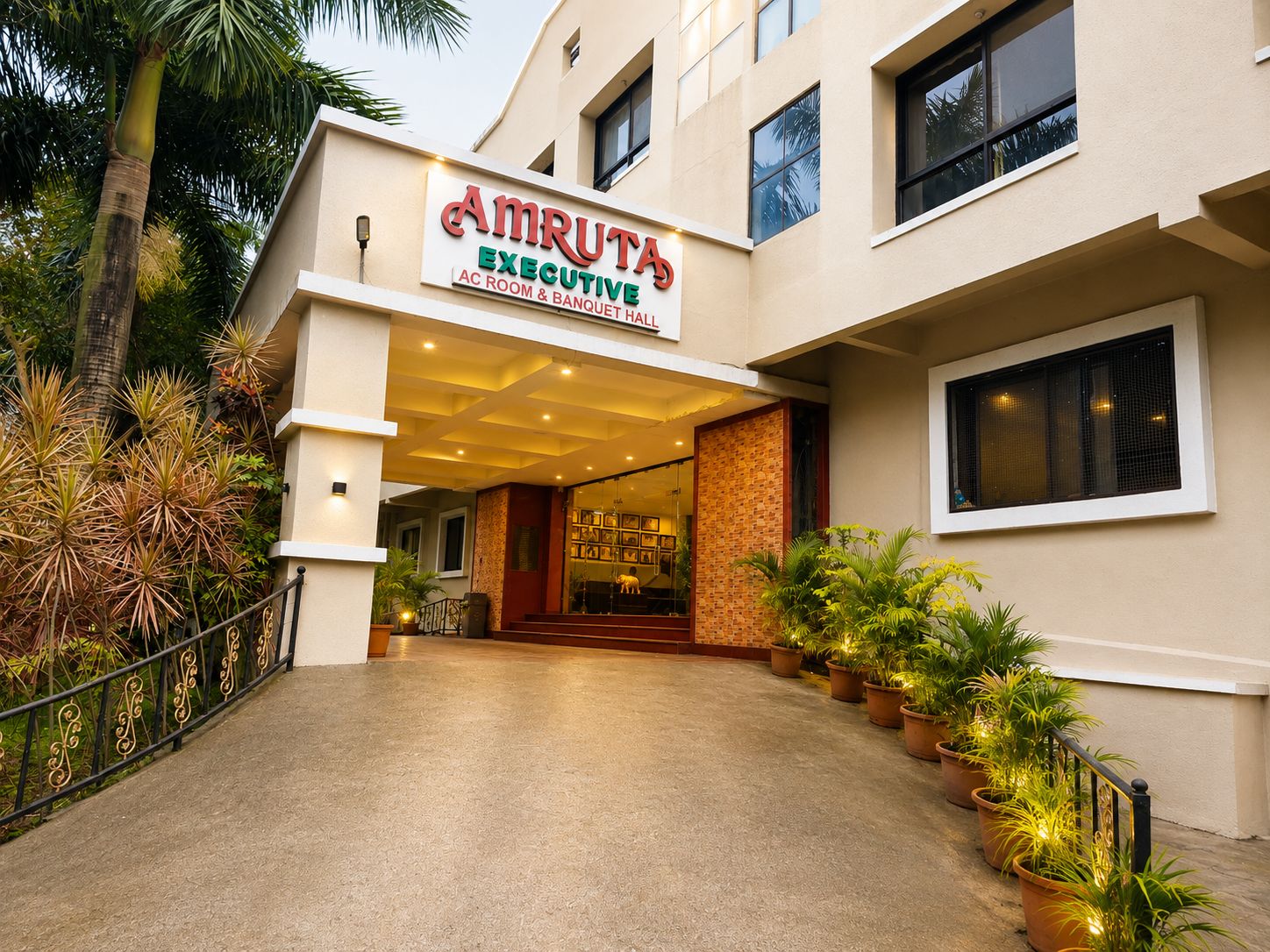 Entrada de un hotel con un cartel que dice 'Amruta Executive AC Room & Banquet Hall'.