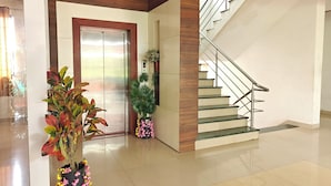 Un vestíbulo moderno con un muro decorativo de madera, una escalera y una cámara de seguridad.