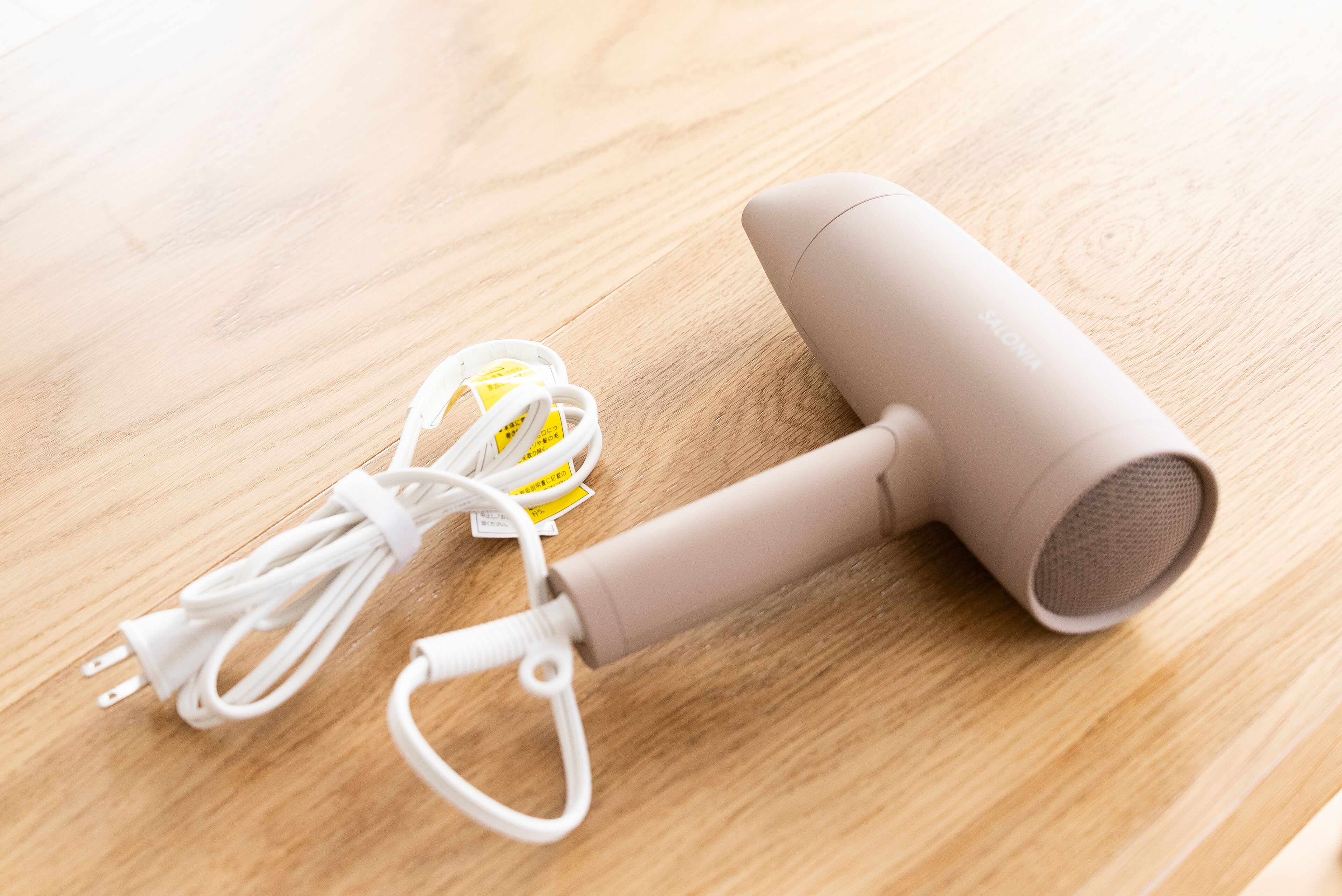 A hair dryer with a cord and a power strip on a wooden surface.
