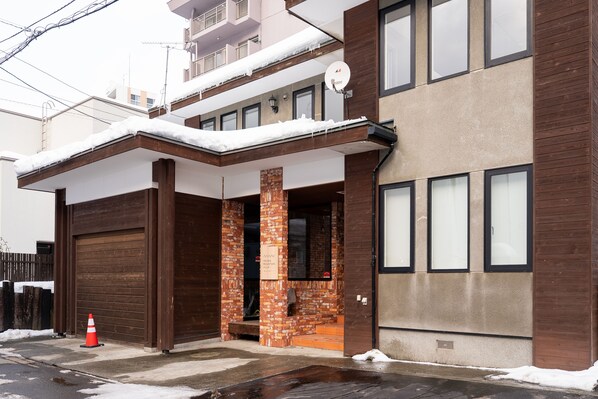 Un bâtiment à deux étages doté d’une porte de garage, de piliers en briques et d’une antenne parabolique.