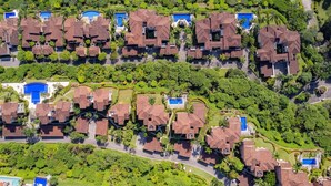 Une vue aérienne d’un quartier résidentiel composé de nombreuses maisons, chacune dotée d’une piscine et entourée d’une végétation luxuriante.