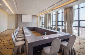 A conference room with a long table, chairs, water bottles, and a projector screen. - Ramada Encore by Wyndham Wuhan (Wuhan)