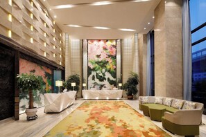 A hotel lobby with a reception desk, seating area, and a large floral mural on the wall. - Ramada Encore by Wyndham Wuhan (Wuhan)