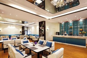 A hotel lobby with seating areas, a reception desk, and a bar. - Ramada Encore by Wyndham Wuhan (Wuhan)
