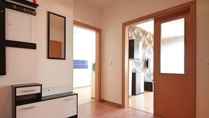 A hallway with a white cabinet, a mirror, and a door leading to another room. - Richie Apartment Near Aquapark (Prague)