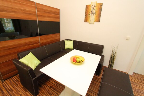 Ein modernes Wohnzimmer mit einem braunen Ledersofa, einem weißen Tisch und einer Obstschale.