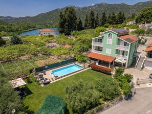 Un bâtiment à deux étages doté d’une piscine, entouré de verdure et de montagnes.