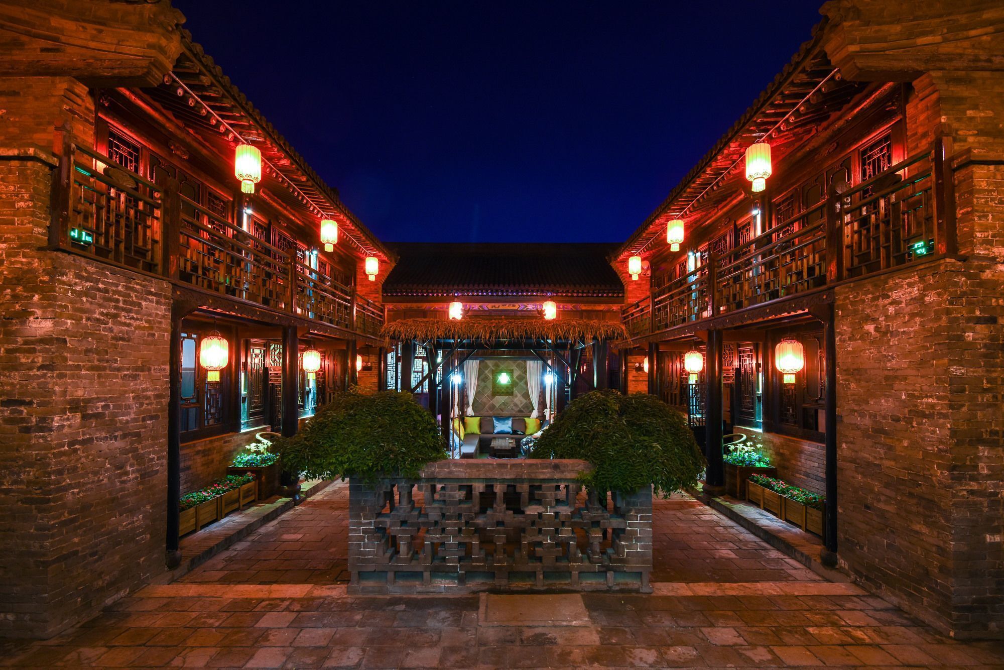 A traditional courtyard with brick walls, lanterns, and a central seating area.