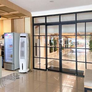 Un vestíbulo de hotel con un gran escaparate de vidrio, una máquina expendedora y un aire acondicionado independiente.