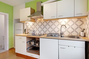 Cozinha com armários brancos, pia de aço inoxidável e backsplash revestido de azulejos.