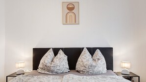 Un lit bien fait, avec une literie à motifs, une tête de lit sombre et deux lampes de chevet.