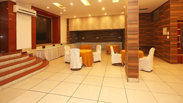 A conference room with tiered seating, a stage, and a wooden accent wall. - OYO 11451 Hotel Auston (Gurugram)