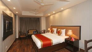 A hotel room with a large bed, two bedside tables, a ceiling fan, and a TV mounted on the wall. - OYO 11451 Hotel Auston (Gurugram)
