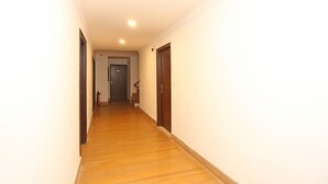 A narrow hallway with wooden flooring and plain walls. - OYO 11451 Hotel Auston (Gurugram)