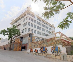 Un edificio de varios pisos con fachada de piedra y un gran portón decorativo.