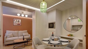 Uma sala de estar moderna com sofá, mesa de centro e área de jantar com cadeiras e uma mesa posta para dois.