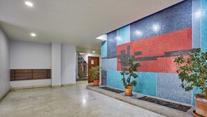 Um hall amplo com parede revestida de azulejos, plantas em vasos e uma escada.