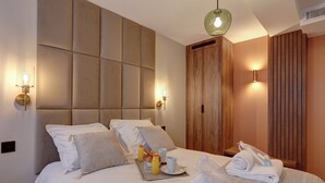 Quarto de hotel com uma cama grande, um guarda-roupa de madeira e uma bandeja de café da manhã com toalhas e um suco de laranja.