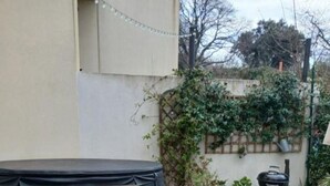Une terrasse en bois avec une table et des chaises, entourée de verdure et agrémentée d’un barbecue.