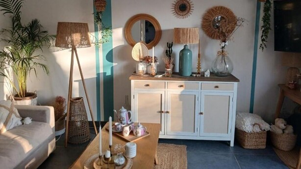 Un salon comprenant un canapé, une table basse et des objets de décoration. On y trouve également un meuble avec des tiroirs et un téléviseur fixé au mur.