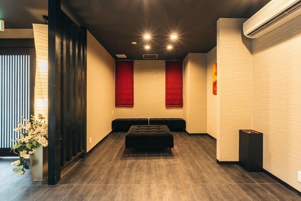 Un hall d’hôtel moderne avec un banc en bois foncé, un mur d’accent rouge et un grand appareil de climatisation.