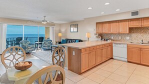 A modern kitchen with wooden cabinets, a central island, and a view of the ocean. - Casa de Playa 206 - Beach Front Condo (Indian Rocks Beach)