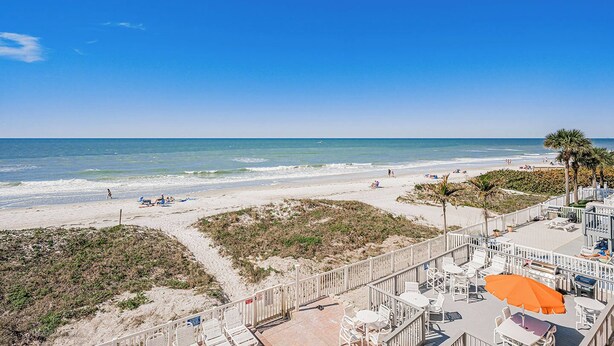 A beach view with a pathway leading to a seating area with umbrellas. - Casa de Playa 206 - Beach Front Condo (Indian Rocks Beach)