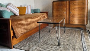 Et hyggeligt rum med en seng, et lille bord, et træskab og en lampe.