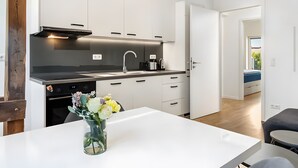 Eine moderne Küche mit weißen Schränken, einer schwarzen Arbeitsplatte und einer Vase mit Blumen auf dem Tisch.