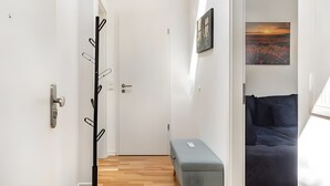 Ein Flur, der in ein Schlafzimmer mit einem Bett, einer Bank und einem Kleiderständer führt.