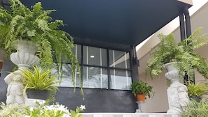 A covered outdoor area with potted plants and a stone bench. - IT Me Keawanong Hotel (Nakhon Ratchasima)
