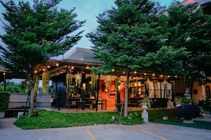 An outdoor restaurant with tables and chairs, surrounded by greenery and trees. - IT Me Keawanong Hotel (Nakhon Ratchasima)
