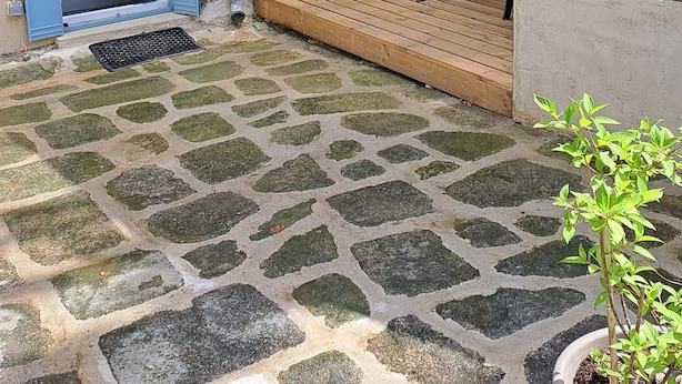 A courtyard with a stone-tiled floor, a small table with chairs, a blue door, and a window with a view of trees. - Sunset de Bénévent, country cottage for 4 to 6 people (Bénévent-l'Abbaye)