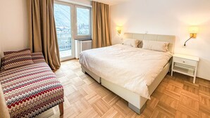 A hotel room with a large bed, two bedside tables, a window with curtains, and a view of the mountains. - Acereto by Interhome (Nassereith)