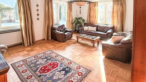 A living room with a wooden parquet floor, a patterned rug, leather sofas, a coffee table, and a hanging light fixture. - Acereto by Interhome (Nassereith)