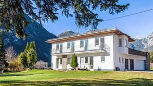 A two-story modern house with a balcony, surrounded by a well-maintained lawn and mountains in the background. - Acereto by Interhome (Nassereith)