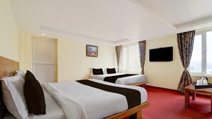 A hotel room with two beds, a television, and a window with curtains. - Classic Abirami Grand Inn (Kodaikanal)