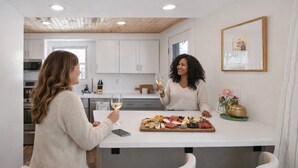 Une cuisine moderne avec des armoires blanches, un plafond en bois et un îlot central agrémenté d’une planche à charcuterie.