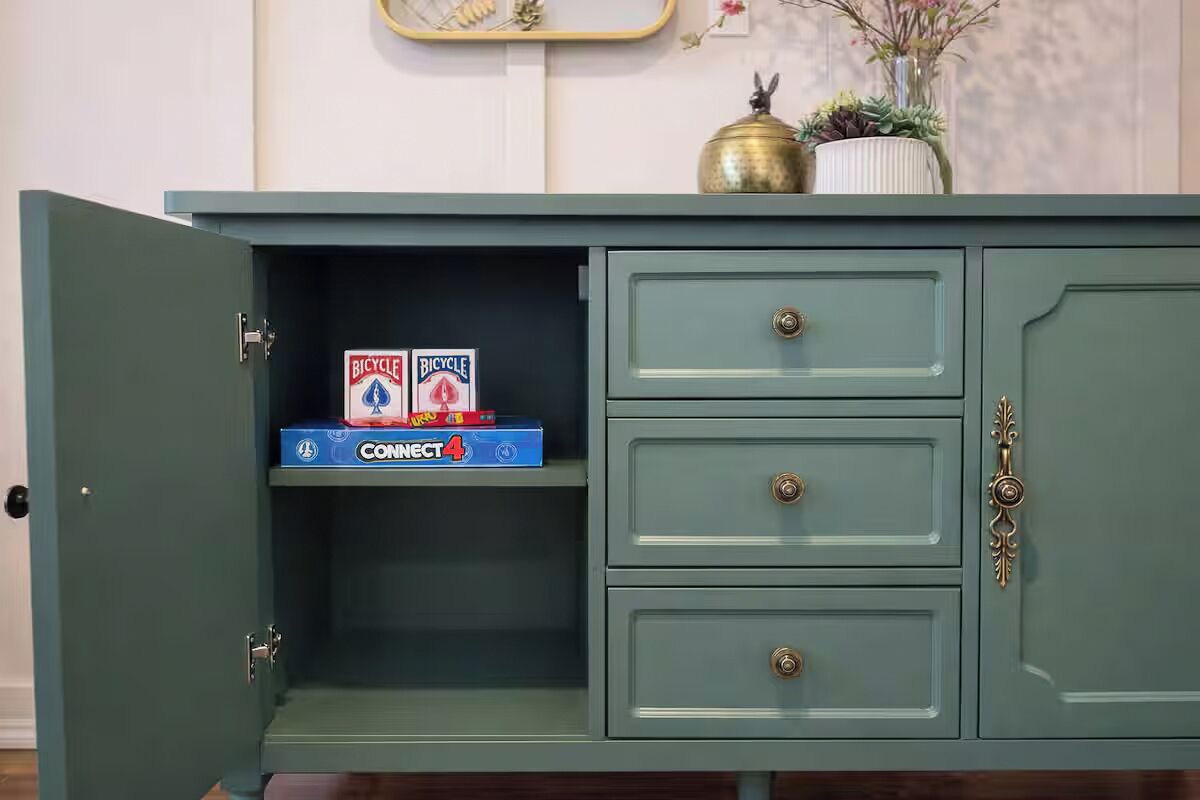 A green cabinet with three drawers and a shelf.