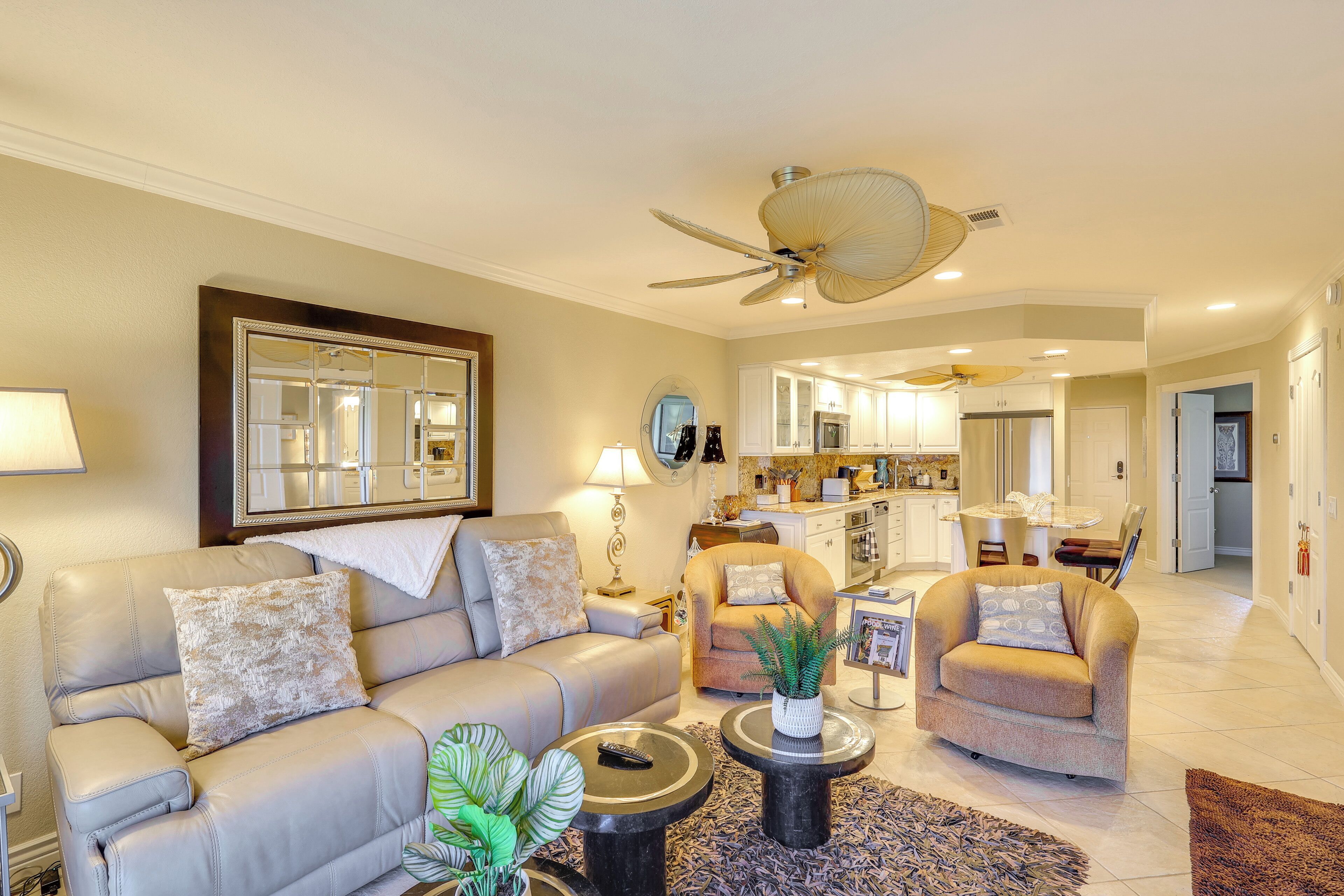 A living room with a sofa, armchairs, a coffee table, and a ceiling fan.