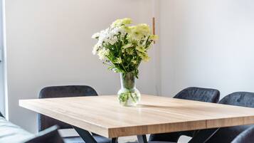 A table with a vase of flowers, a modern chair, and a minimalist room design.